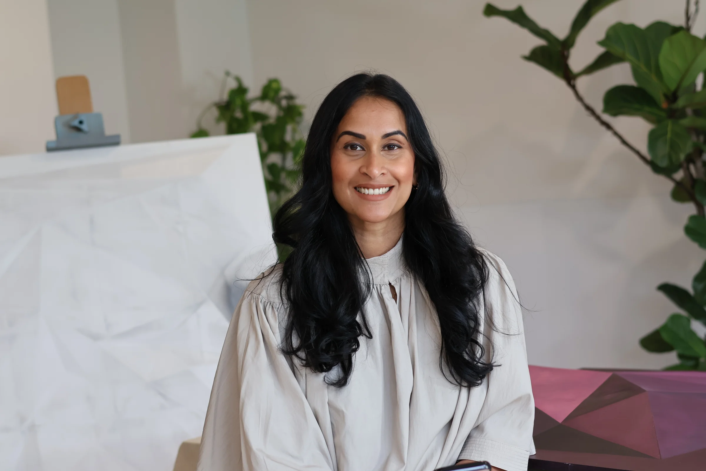 Portrait of Kalani Wijewardana in her studio, seated between geometric relief artworks