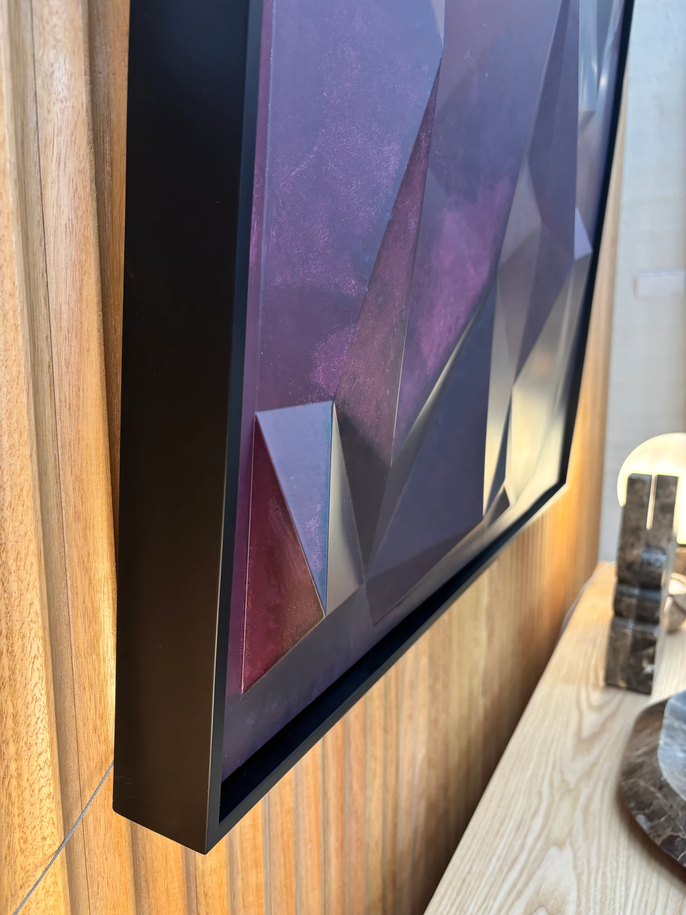 Close-up of the painted facets and black frame against timber