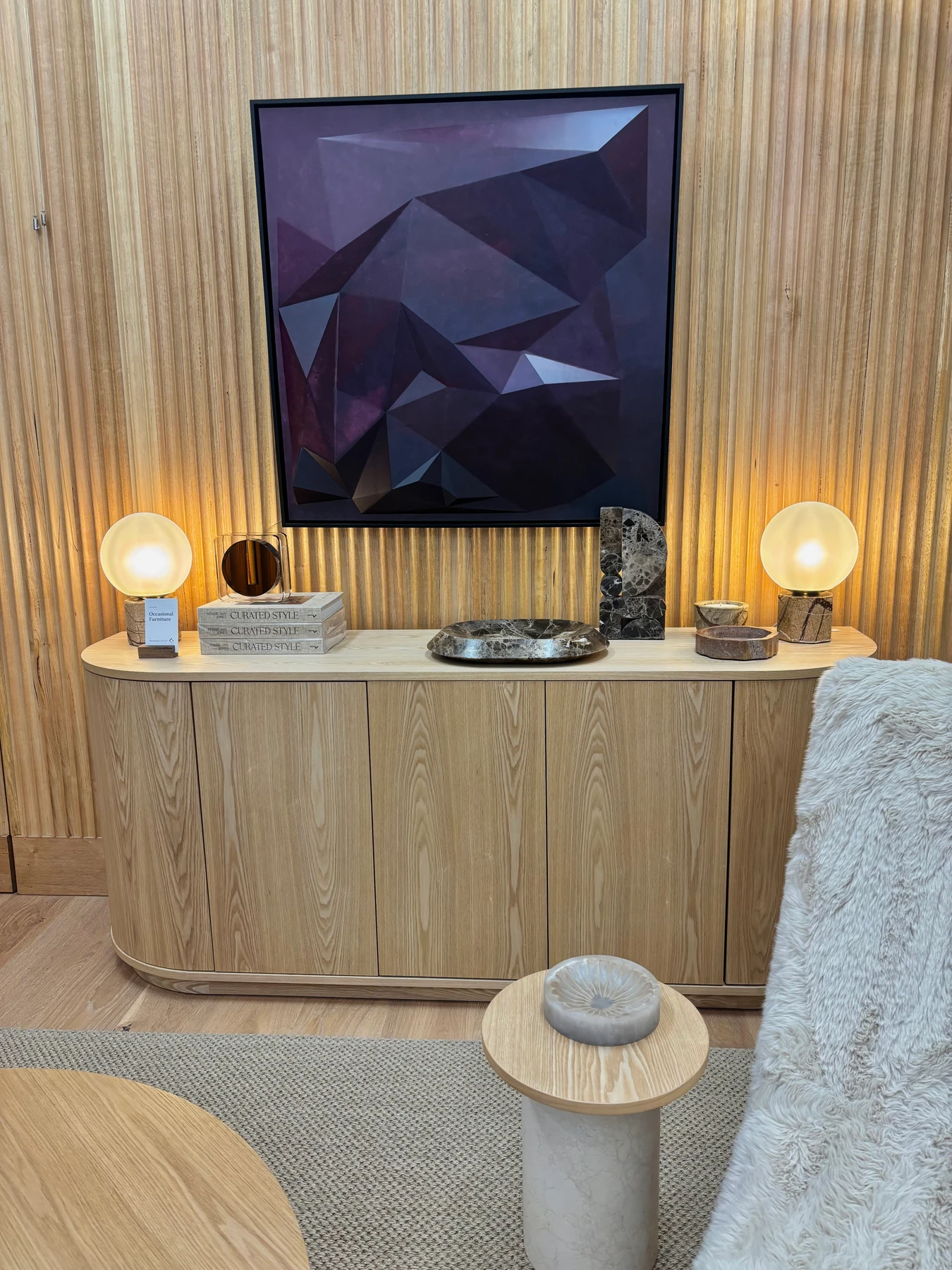 Within Colour above a curved timber sideboard with globe lamps