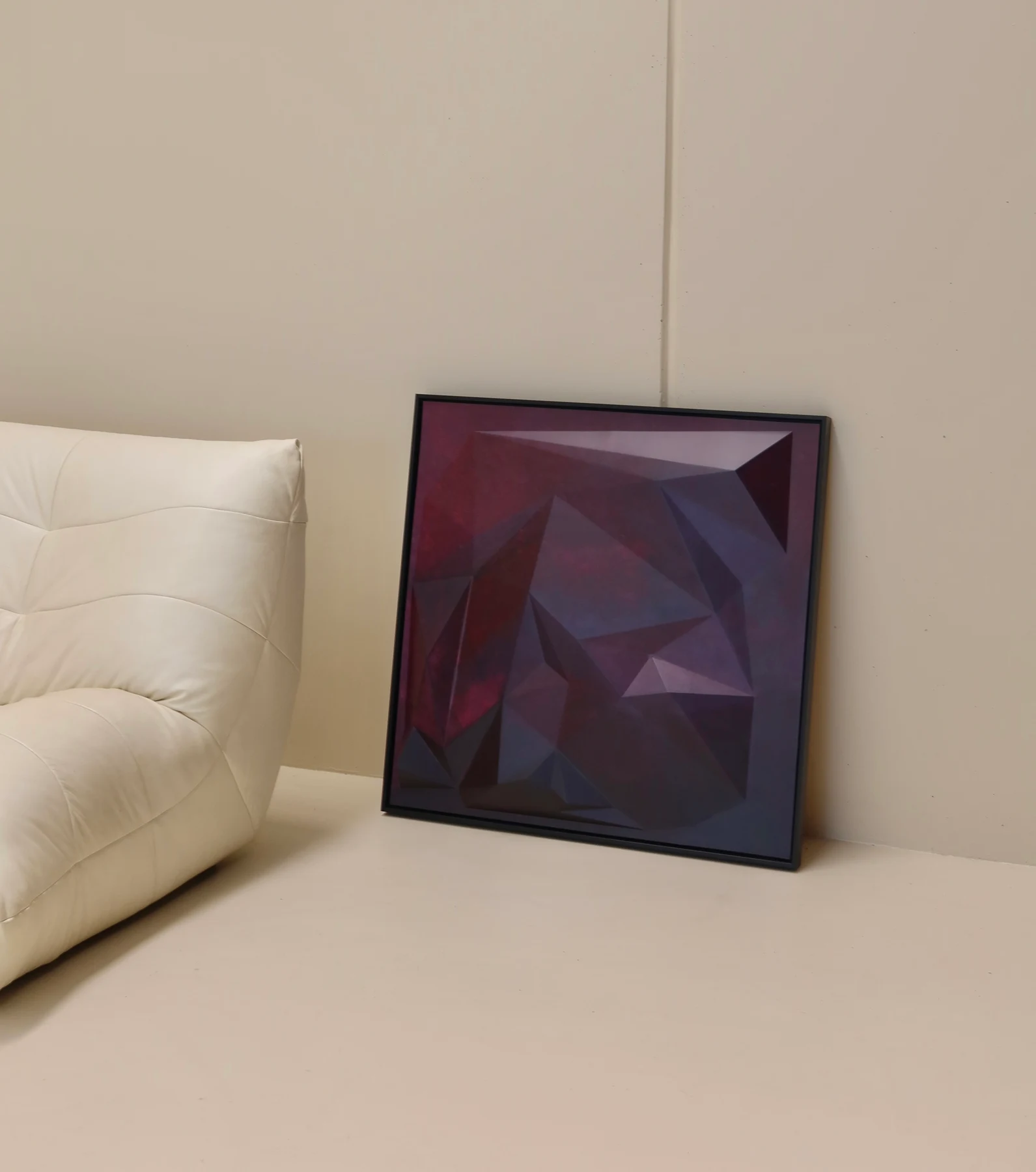 Black-framed burgundy and purple artwork beside a white sofa