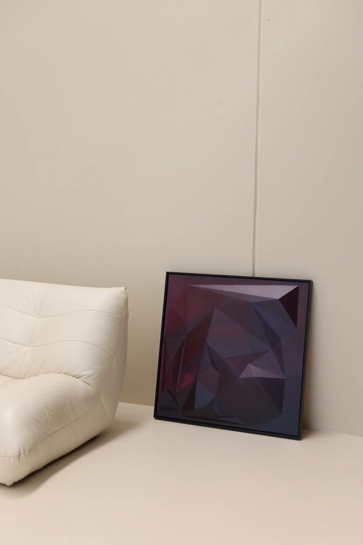 Wider view of the black-framed artwork beside a white sofa