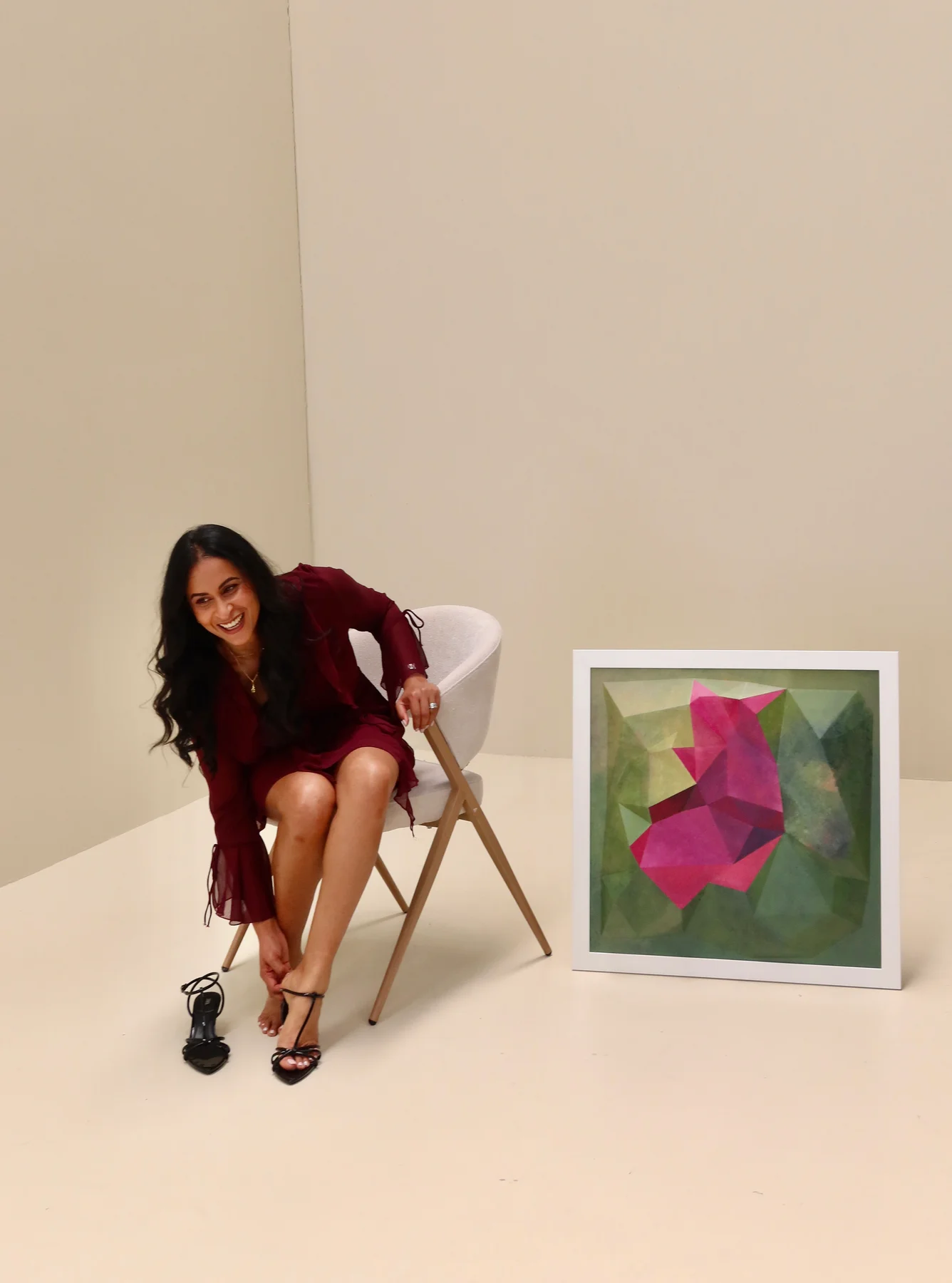White-framed magenta and green artwork beside a person leaning forward from a chair