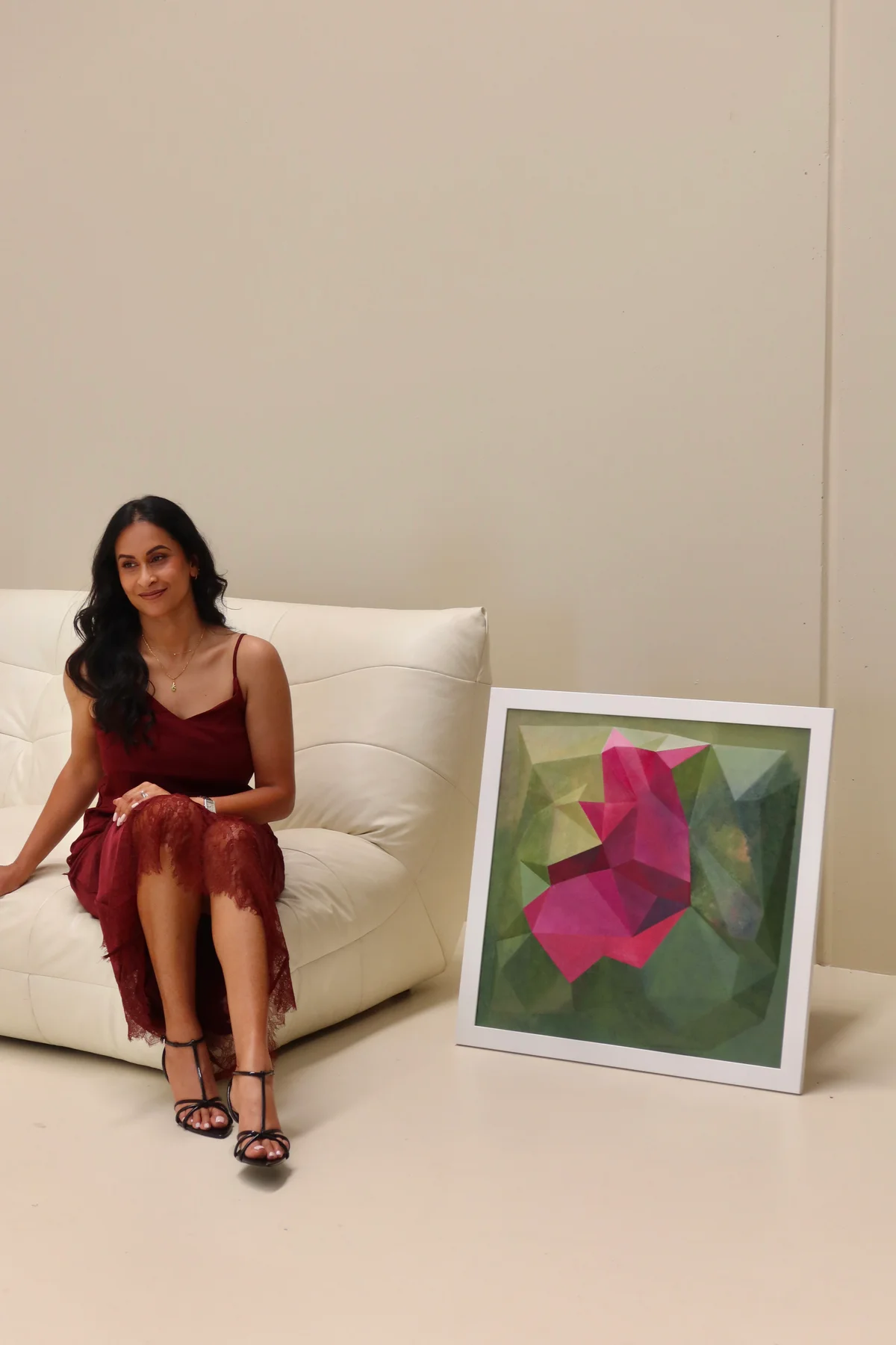 Framed magenta and green artwork beside a person seated on a white sofa